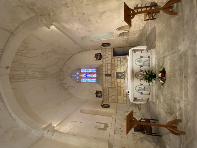 Cœur de l'église Saint-Romain de Triac suite aux travaux en 2020, autel recouvert d'un linge blanc, fleurs, vitrail et pupitres 