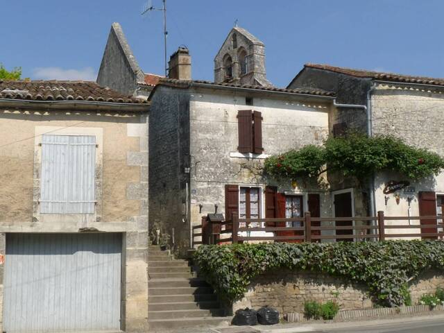 Bourg de Triac, une maison aux volet marrons et balcon végétalisé devant l'église 